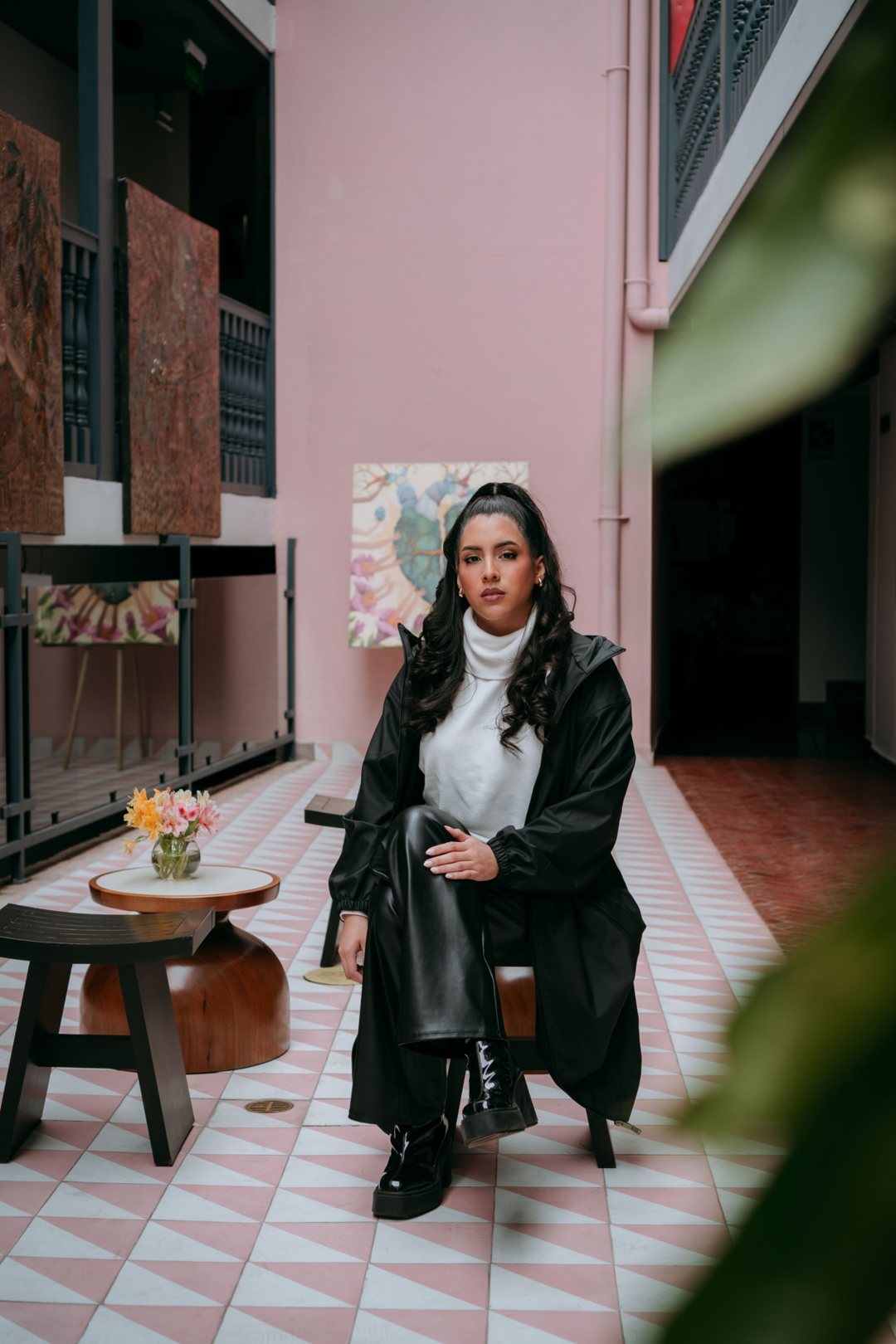 Marcela in a black coat in a courtyard